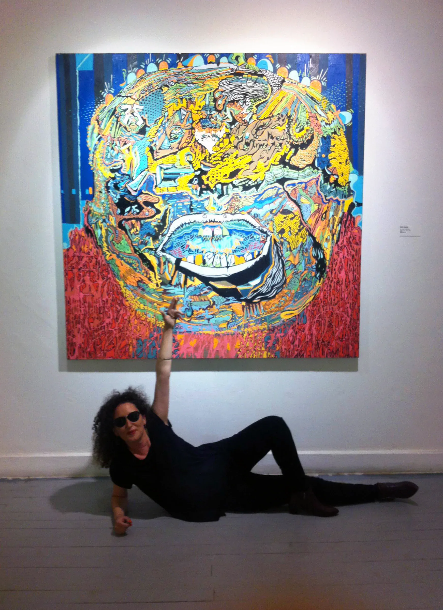 Ece Kalabak beneath one of her paintings
